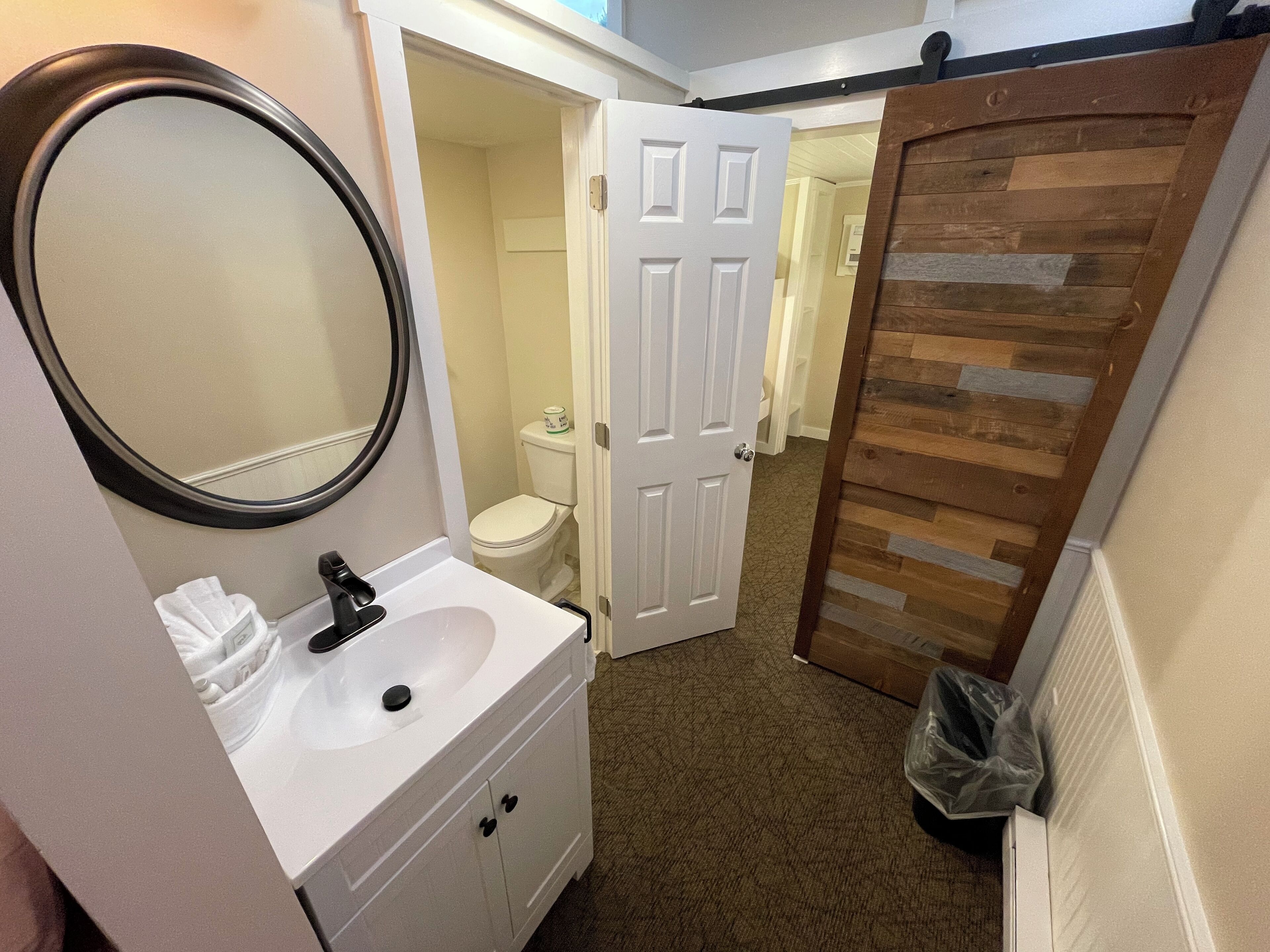 A bathroom with a white sink, mirror, and toilet.