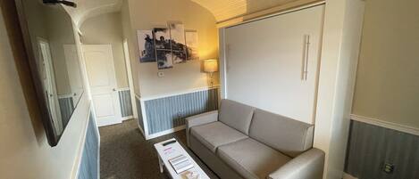 Un espace de vie compact comprenant un canapé, une petite table et un ventilateur de plafond.