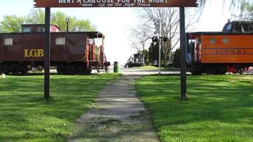 Ein Weg, der zu einem Bahnhof führt, mit einem Schild, auf dem steht: "RENT A CABOOSE FOR THE NIGHT".