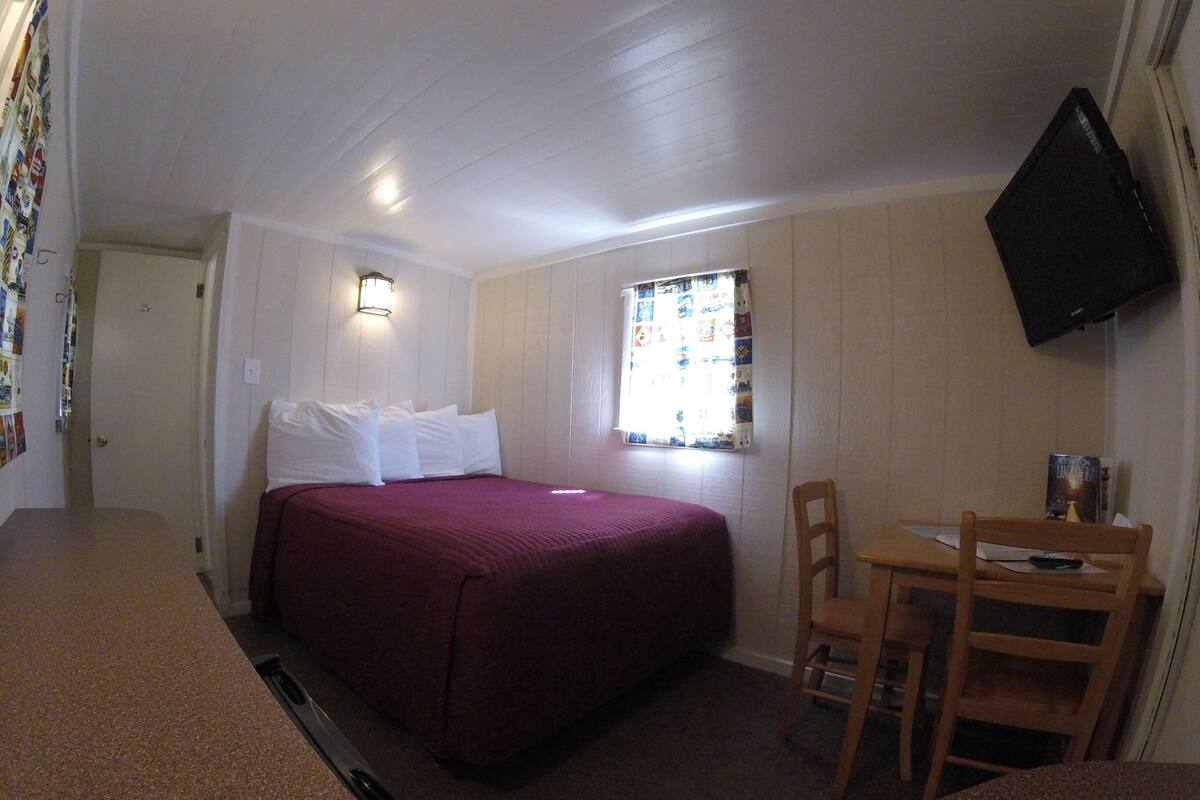 A compact room with a bed, a small table, and a chair.