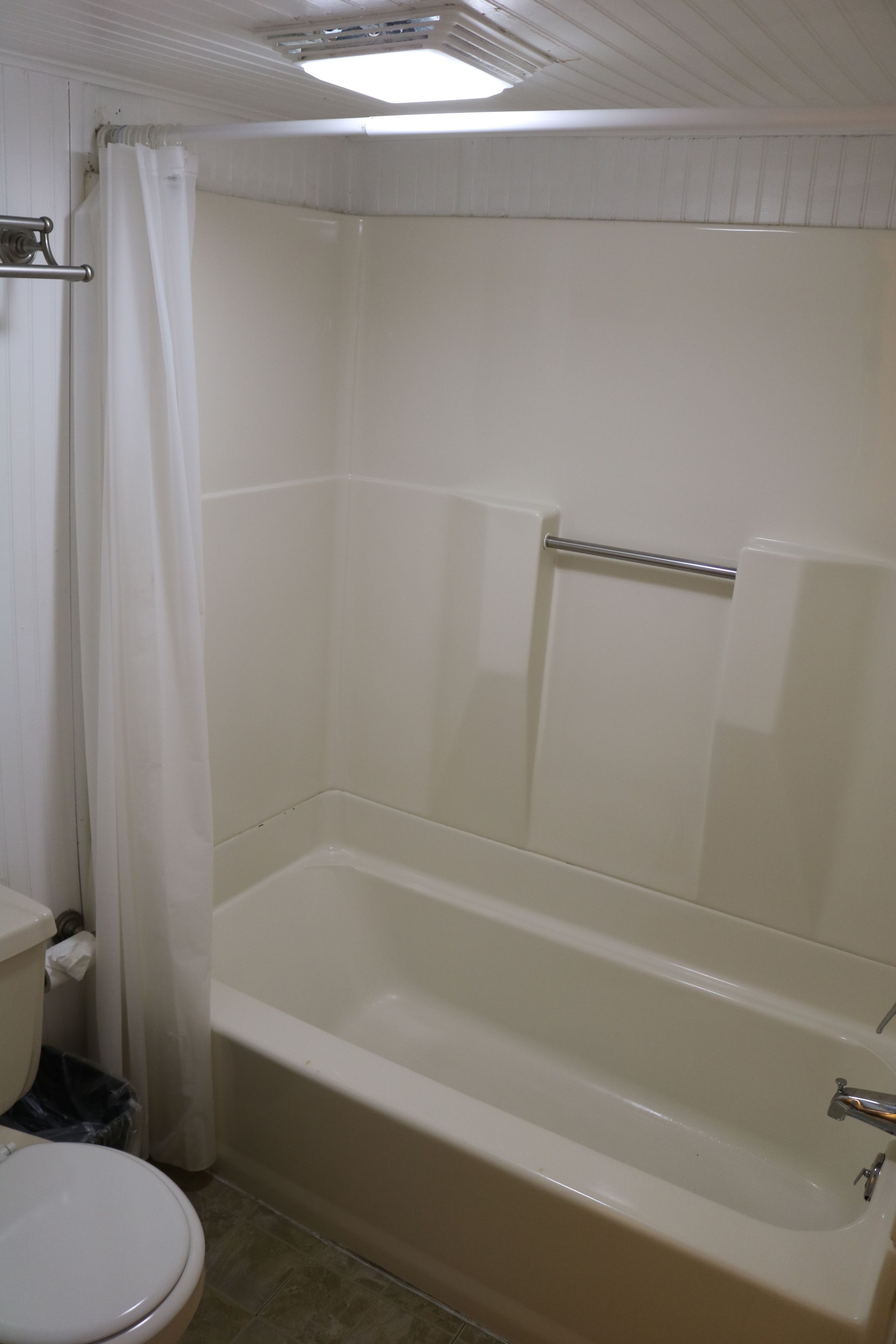A bathroom with a bathtub, toilet, and shower curtain.