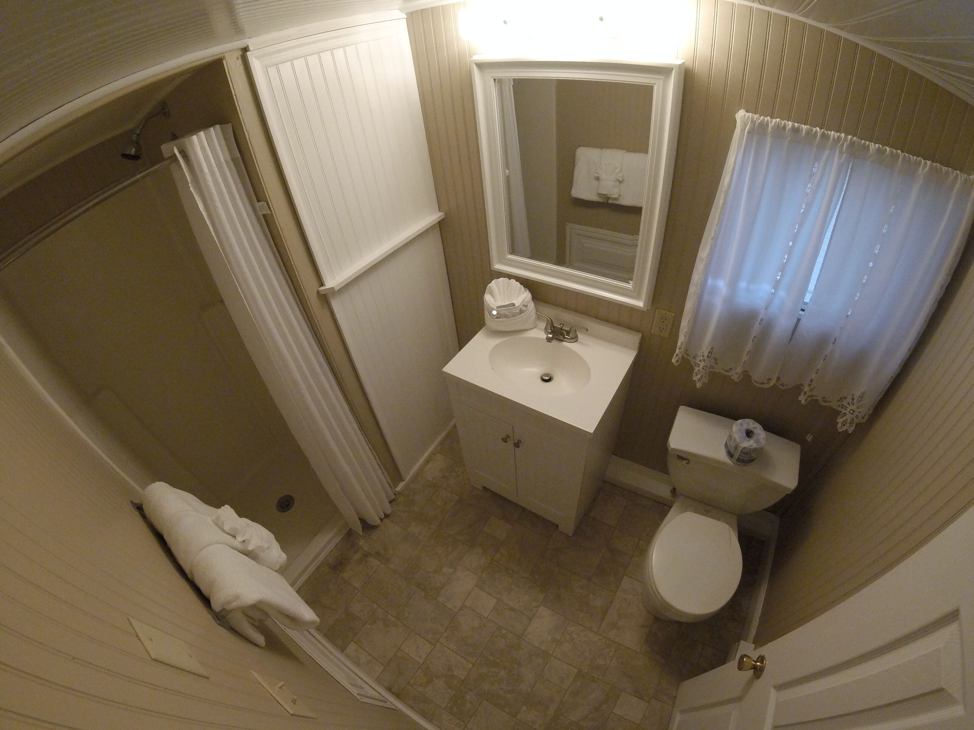 A small bathroom with a sink, toilet, and shower area.