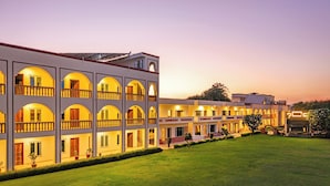 A multi-story hotel with balconies and a well-maintained lawn. - Sterling Amargarh Jodhpur (Luni)
