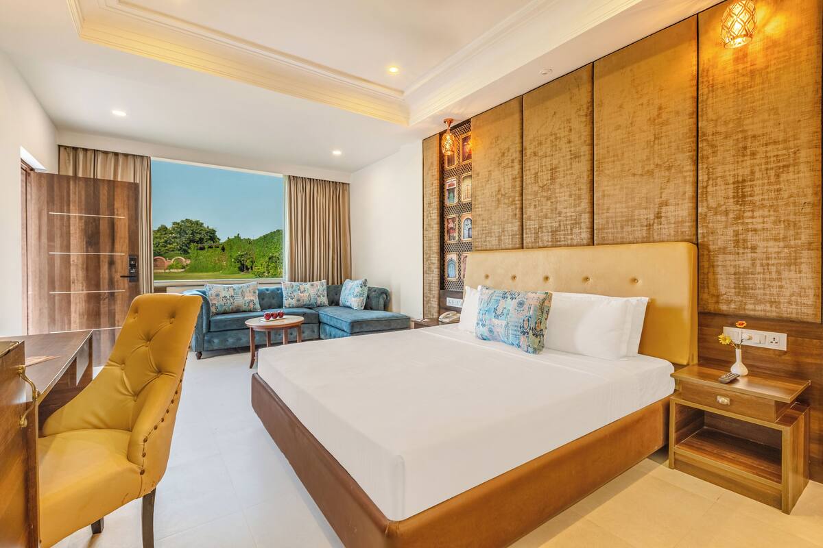 A spacious bedroom with a large bed, a sofa, and a desk.