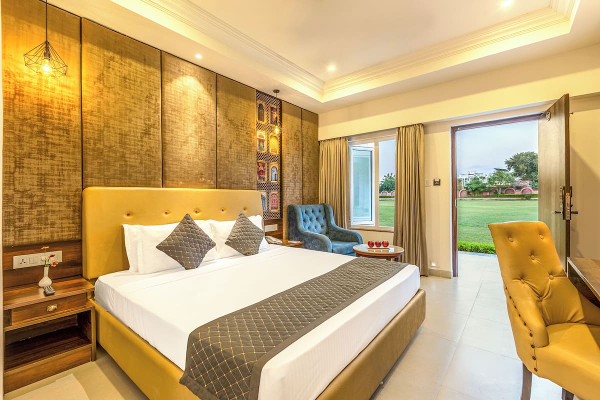 A hotel room with a large bed, a desk, a chair, and a view of the outdoors.