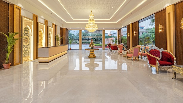 A spacious lobby with a chandelier, a reception desk, and red upholstered chairs. - Sterling Amargarh Jodhpur (Luni)