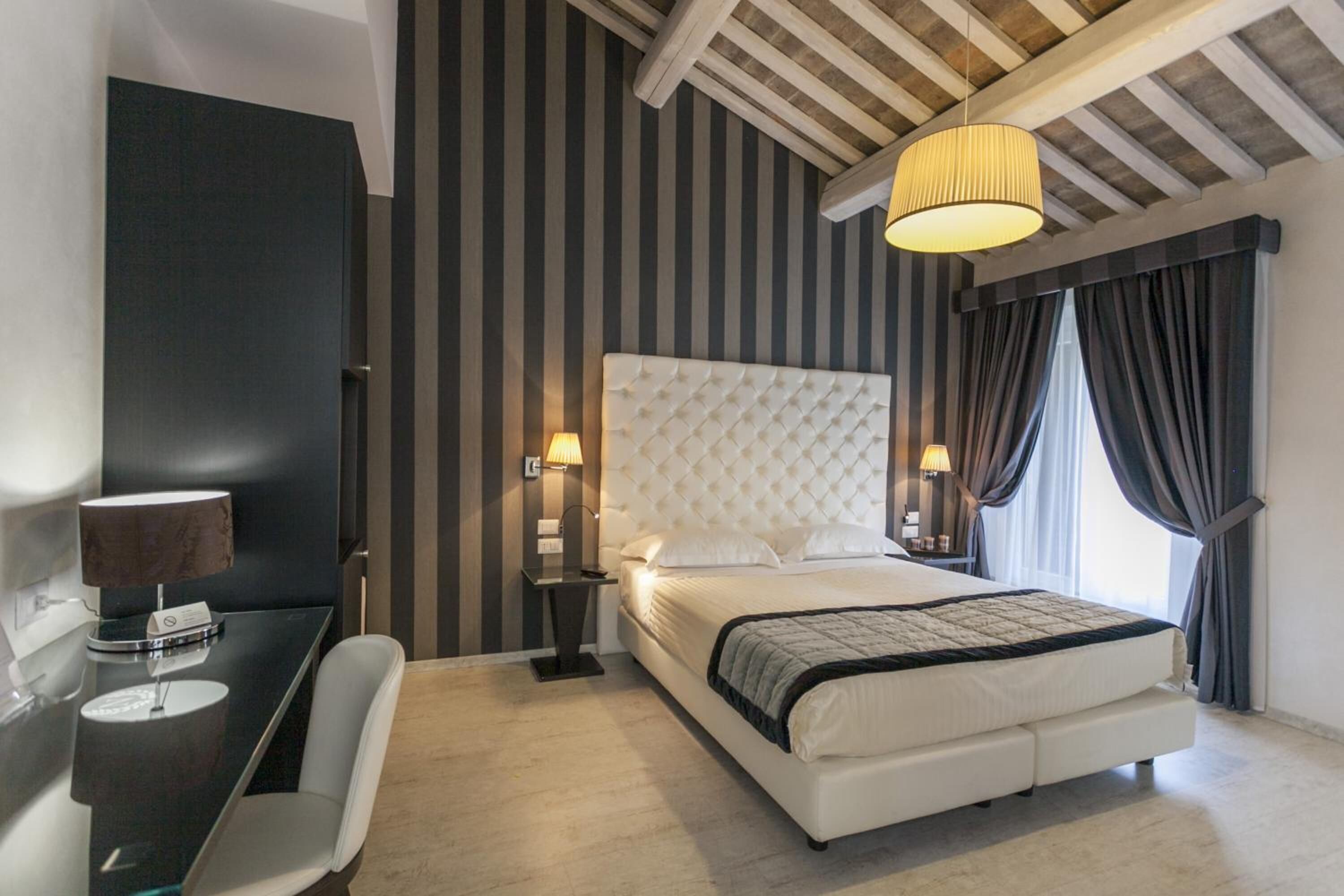 Ein modernes Hotelzimmer mit einem großen Bett, einem Schreibtisch mit Lampe und einem Sessel.