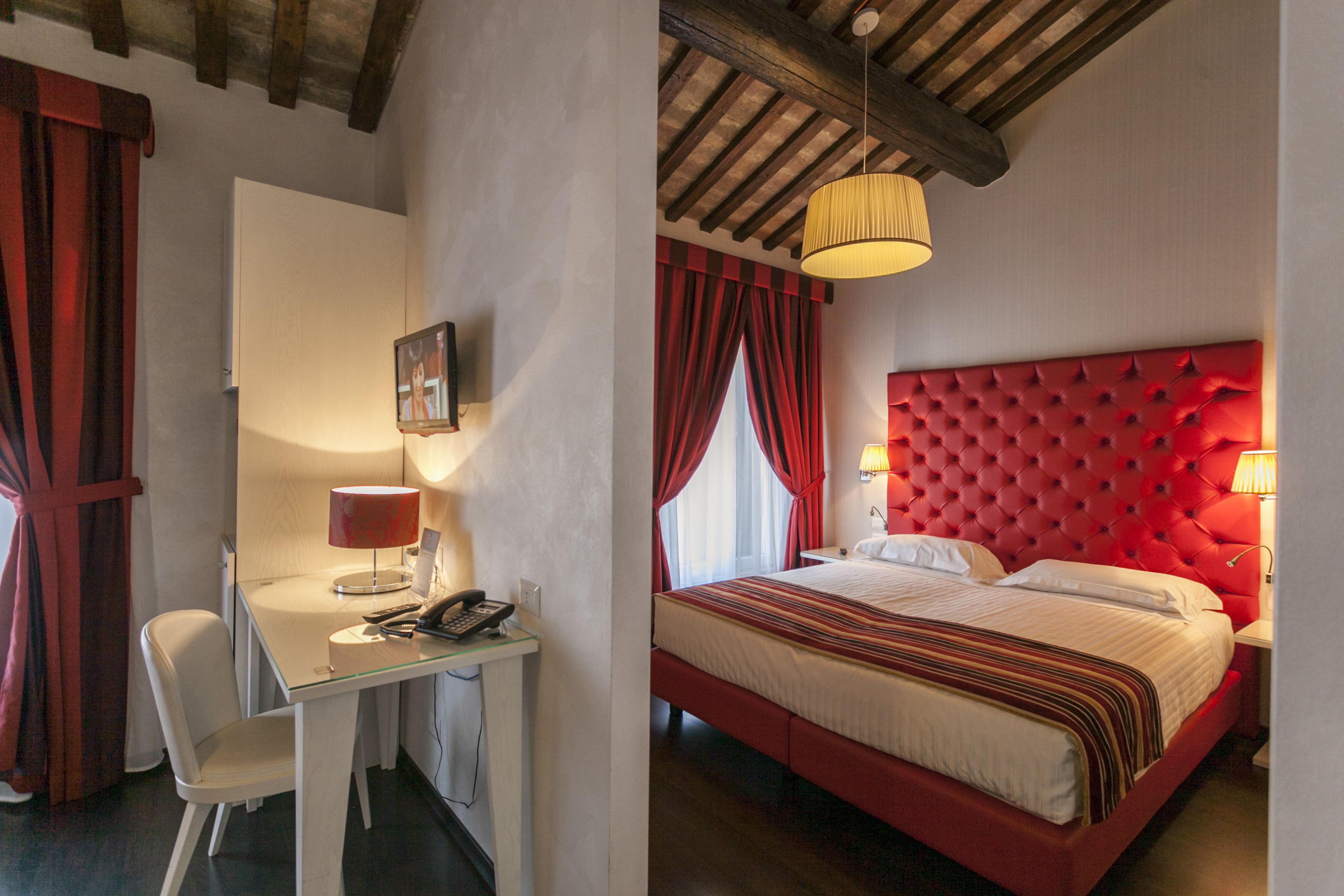 A hotel room with a bed, a desk with a telephone, and a chair.