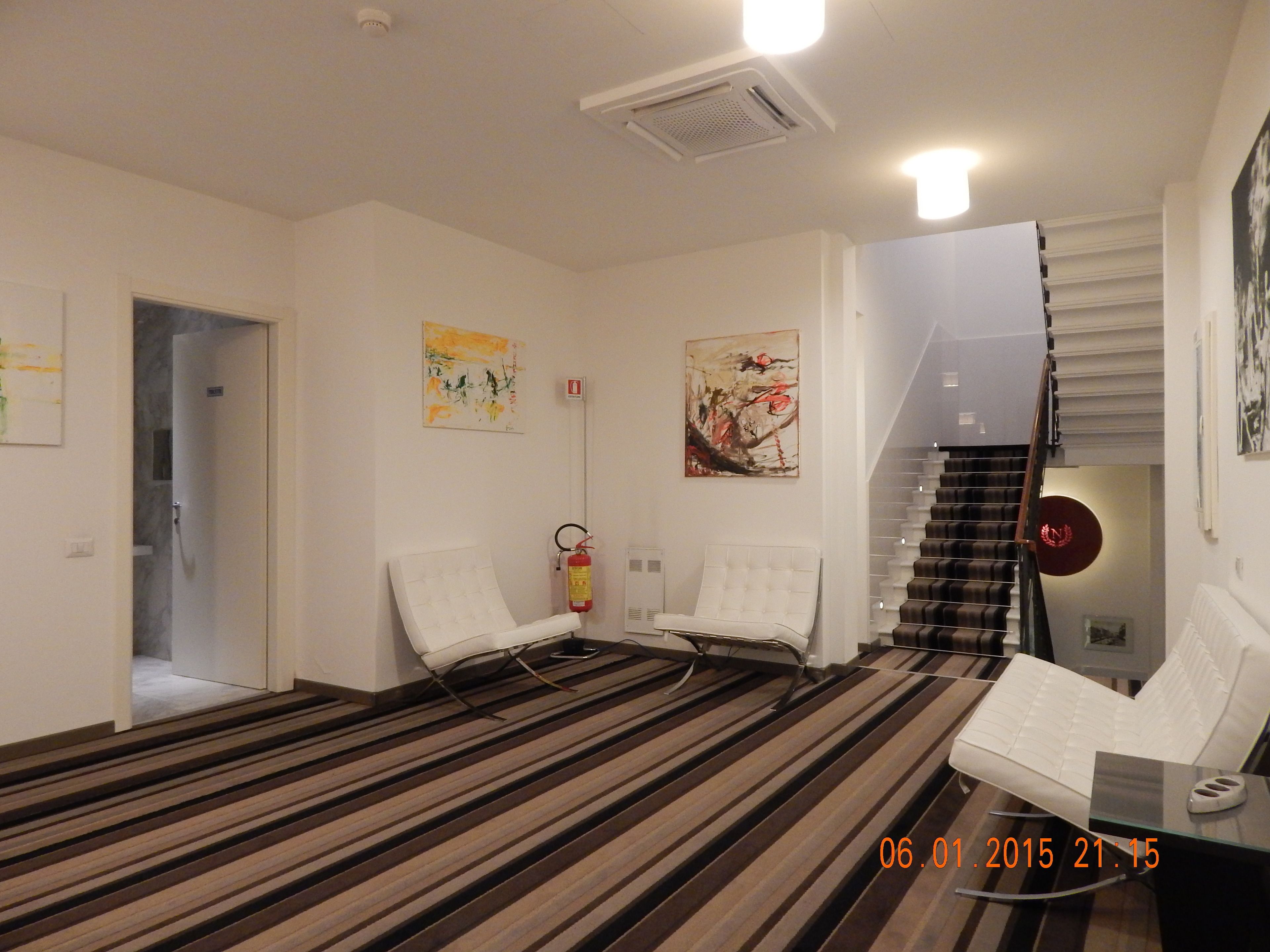 A modern room with a striped carpet, two white chairs, a desk with a computer, and a staircase.