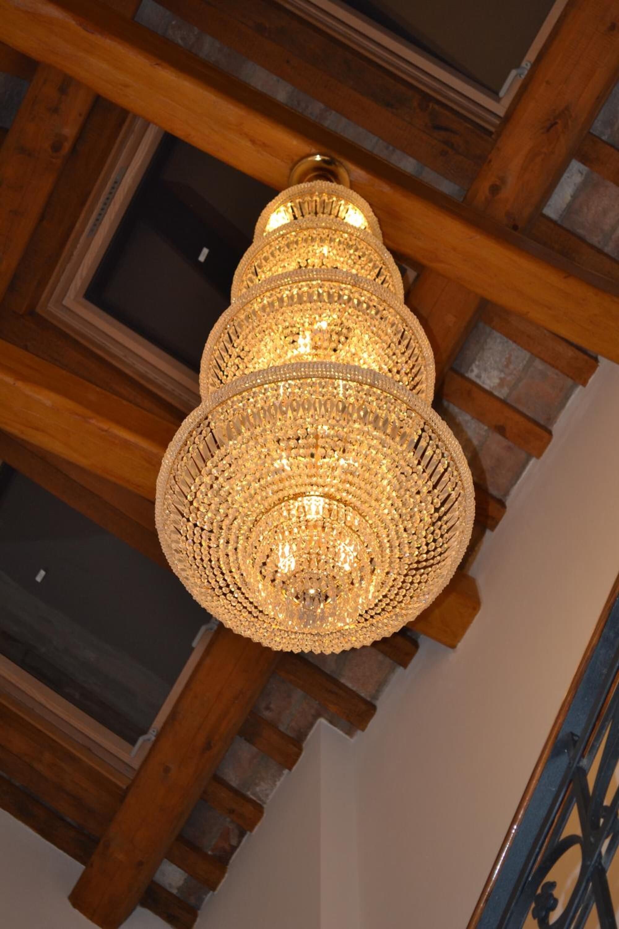 A chandelier with a multi-tiered, intricate design hanging from a wooden ceiling.