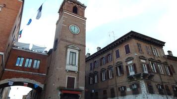 A historic building with a clock tower, a sign reading "BRUNELLI," and a street view with pedestrians.