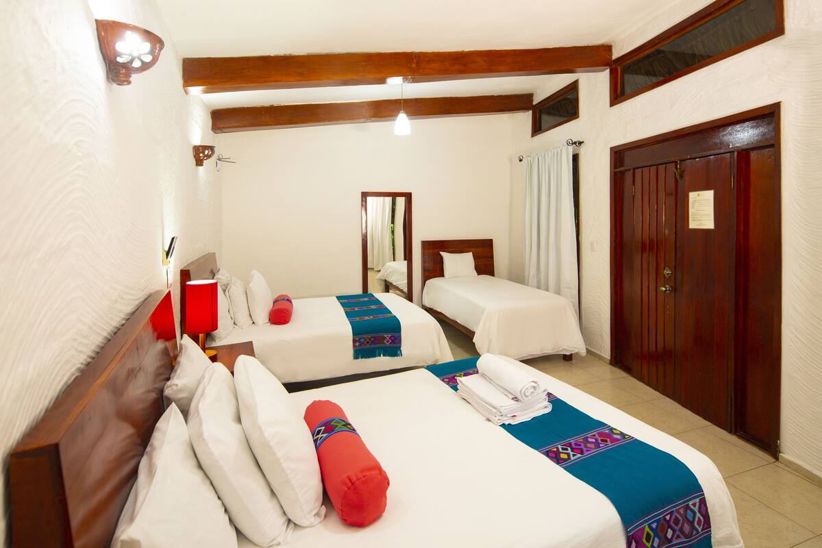Een hotelkamer met twee bedden, houten hoofdborden, een grote spiegel, een kledingkast en een rode lamp.