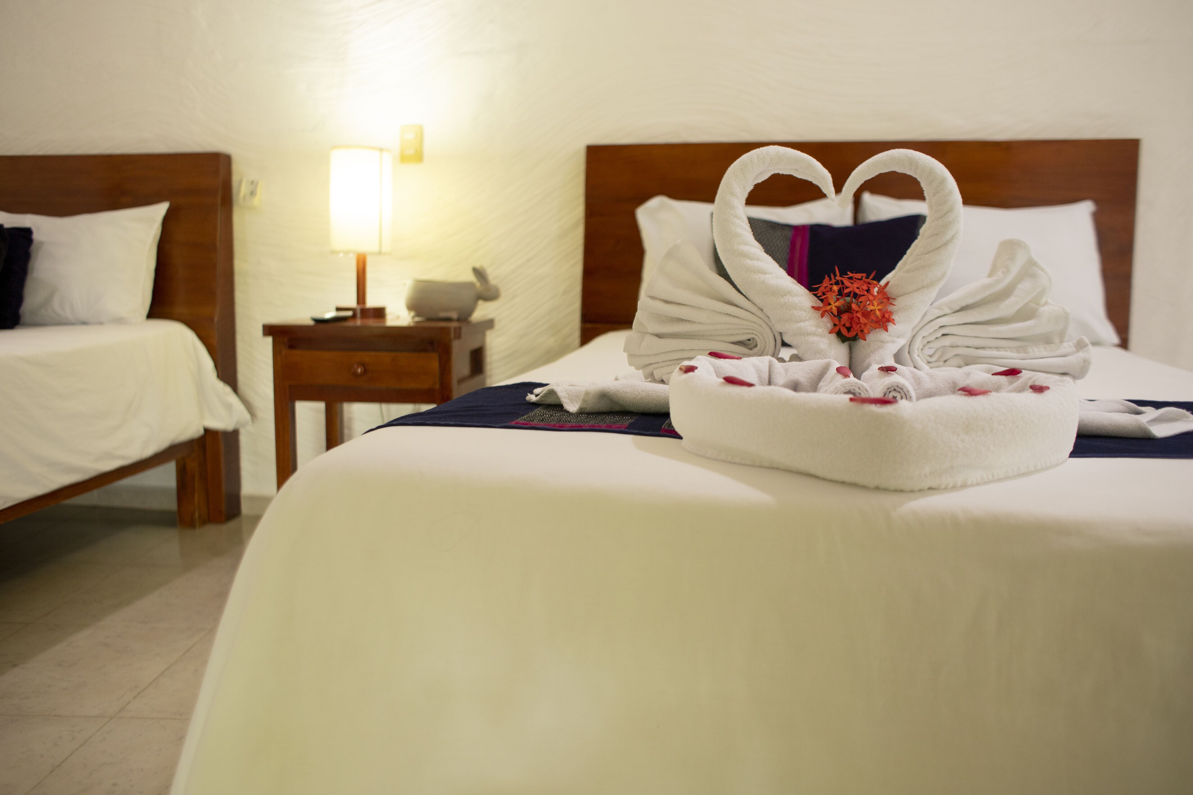 Una habitación de hotel con una cama bien hecha, una mesita de noche con una lámpara y una luz en la pared.