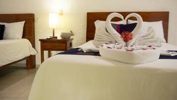 Una habitación de hotel con una cama bien hecha, una mesita de noche con una lámpara y una luz en la pared.
