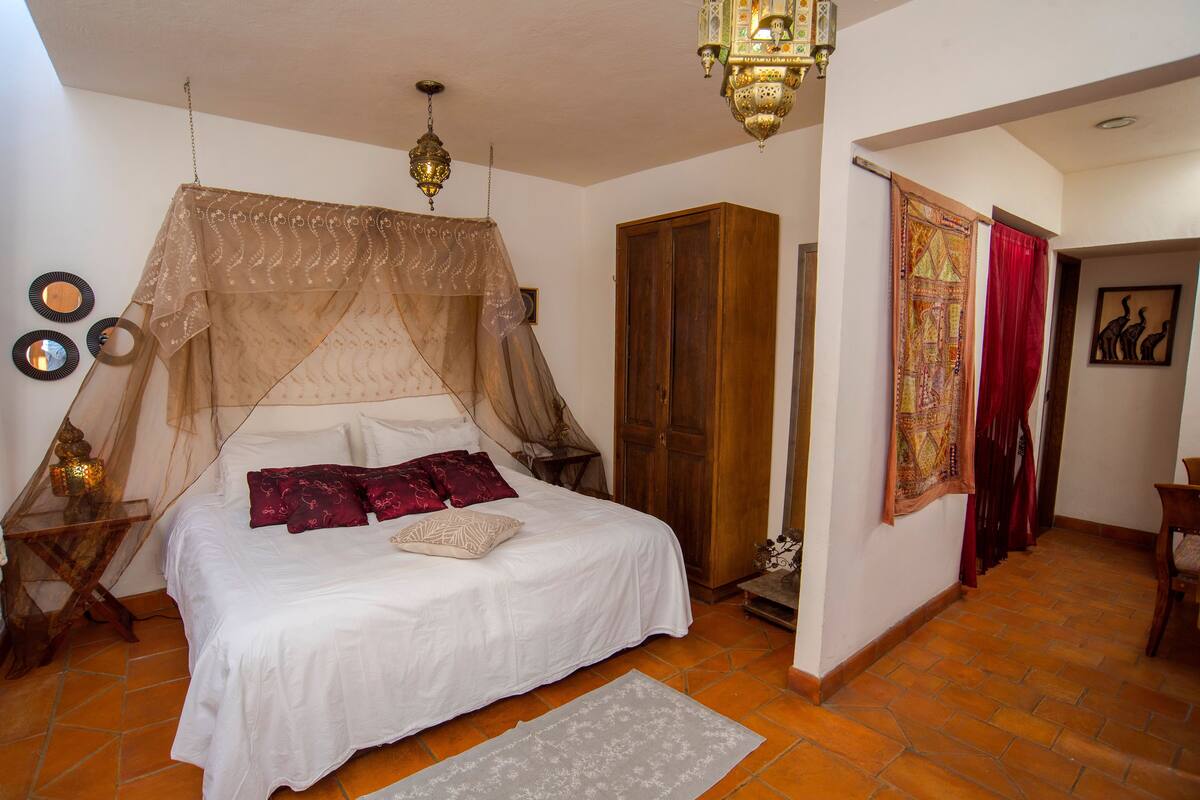Ein Schlafzimmer mit Bett, Schrank, Nachttisch, Lampe und einer Wanddekoration.