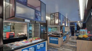 Una barra de desayuno moderna con diversas opciones de comida, una máquina de café y una exposición de frutas.