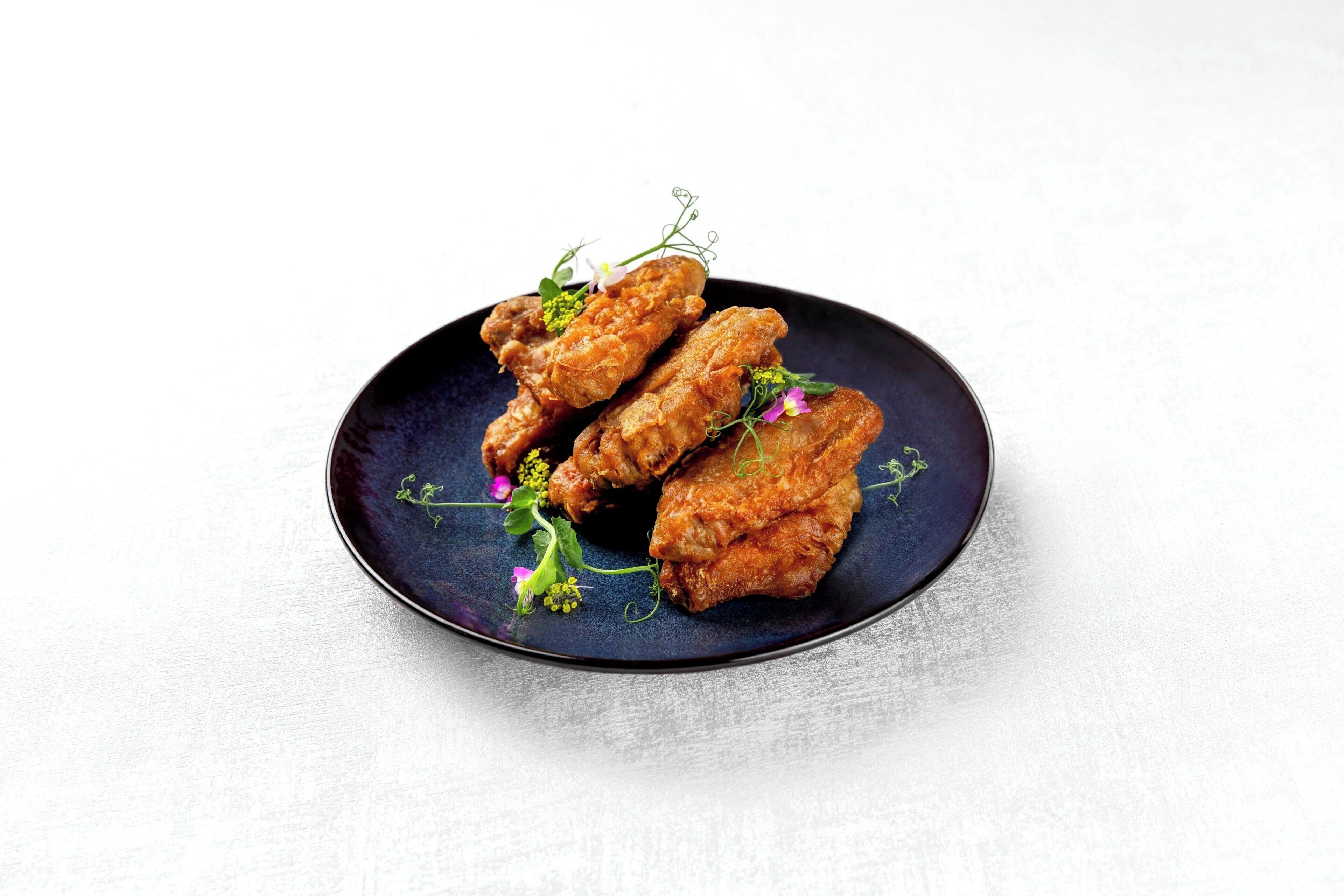 Un plato con pollo frito y flores decorativas.