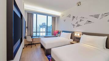 Habitación de hotel con dos camas, un escritorio y un amplio ventanal con vistas a la ciudad.
