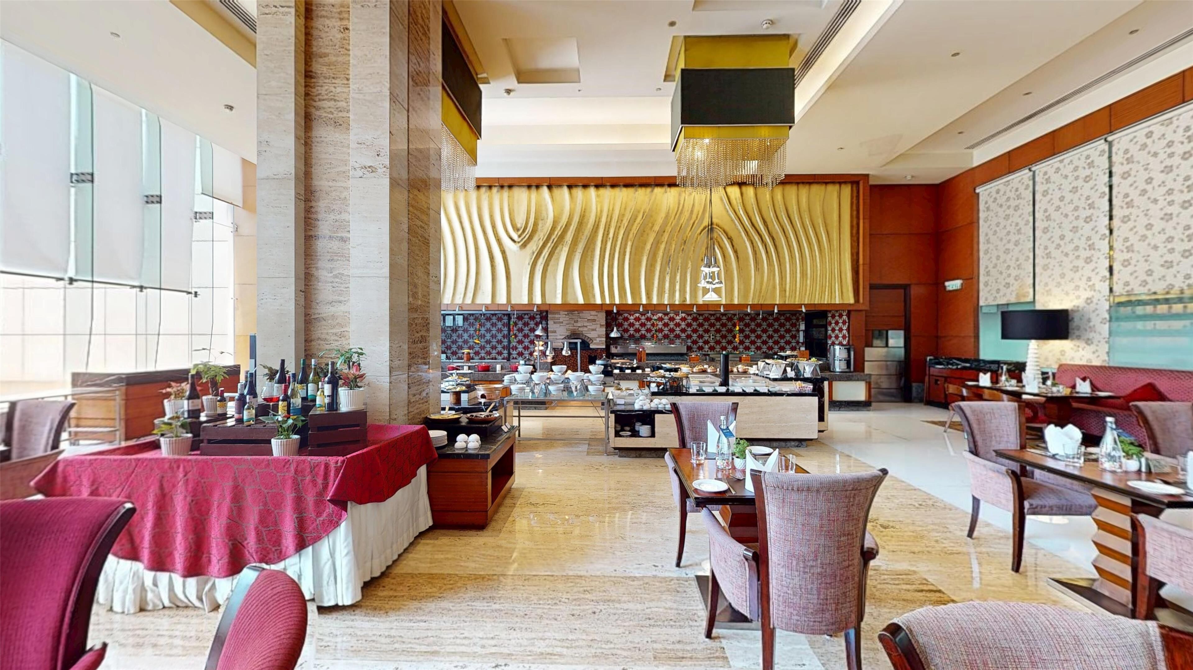 Un vaste espace dédié à la salle à manger, avec de hauts plafonds, un bar central et une vue sur la cuisine.