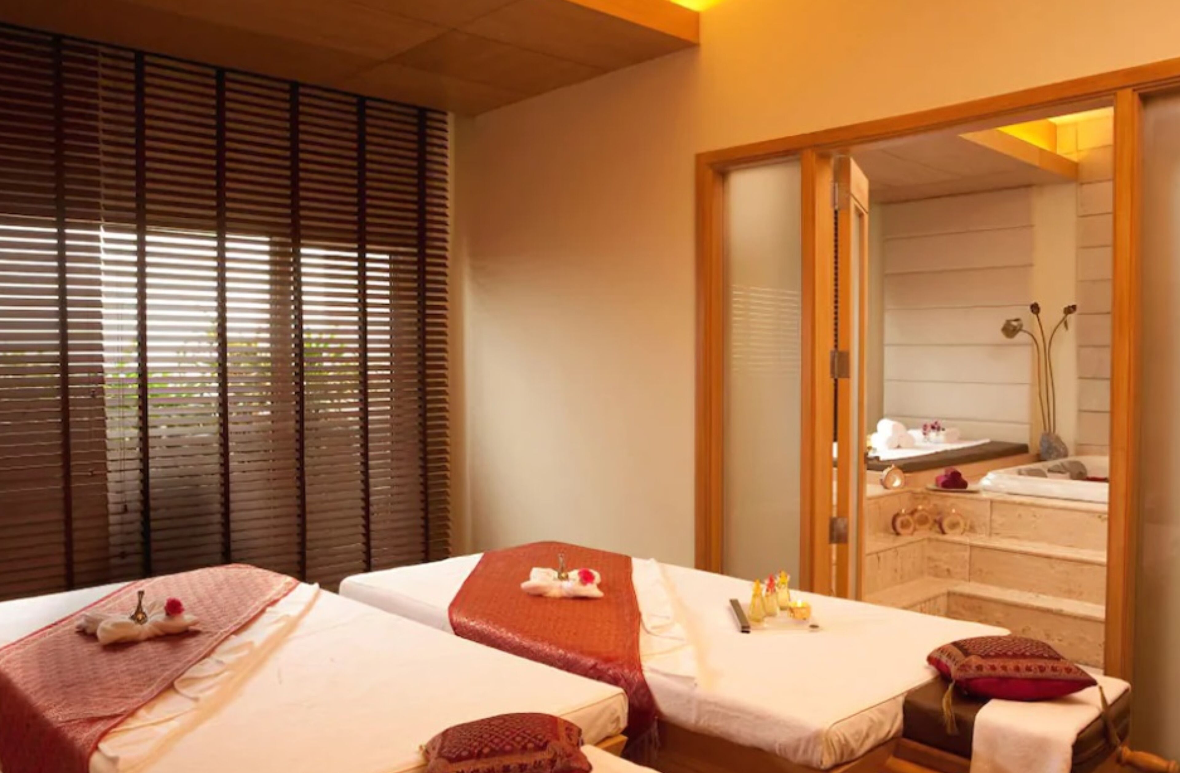 A room with two beds, a massage area, and a view of a spa.