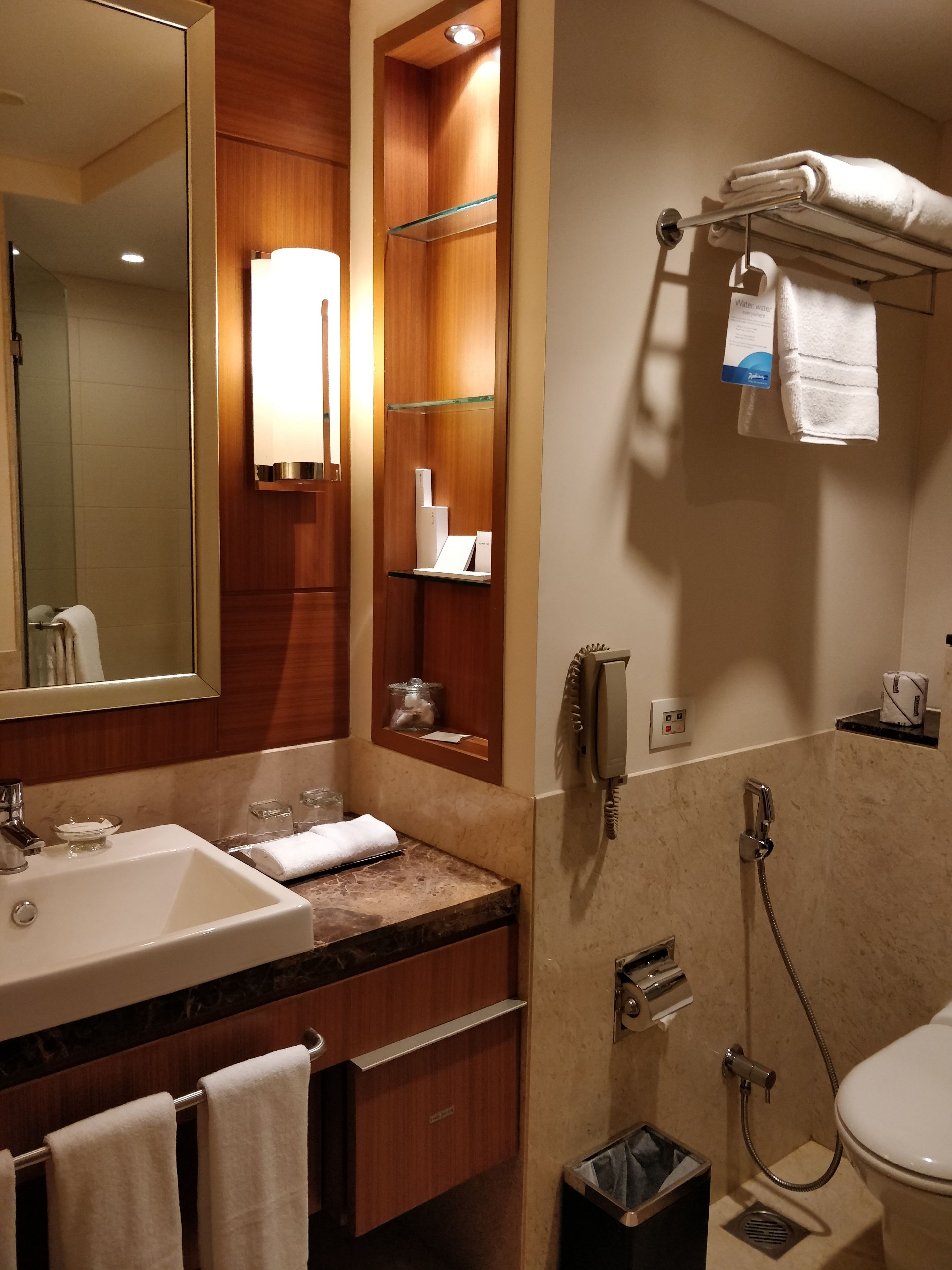 Une salle de bain d’hôtel équipée d’un lavabo, d’un miroir, d’un porte-serviettes et d’une douche.