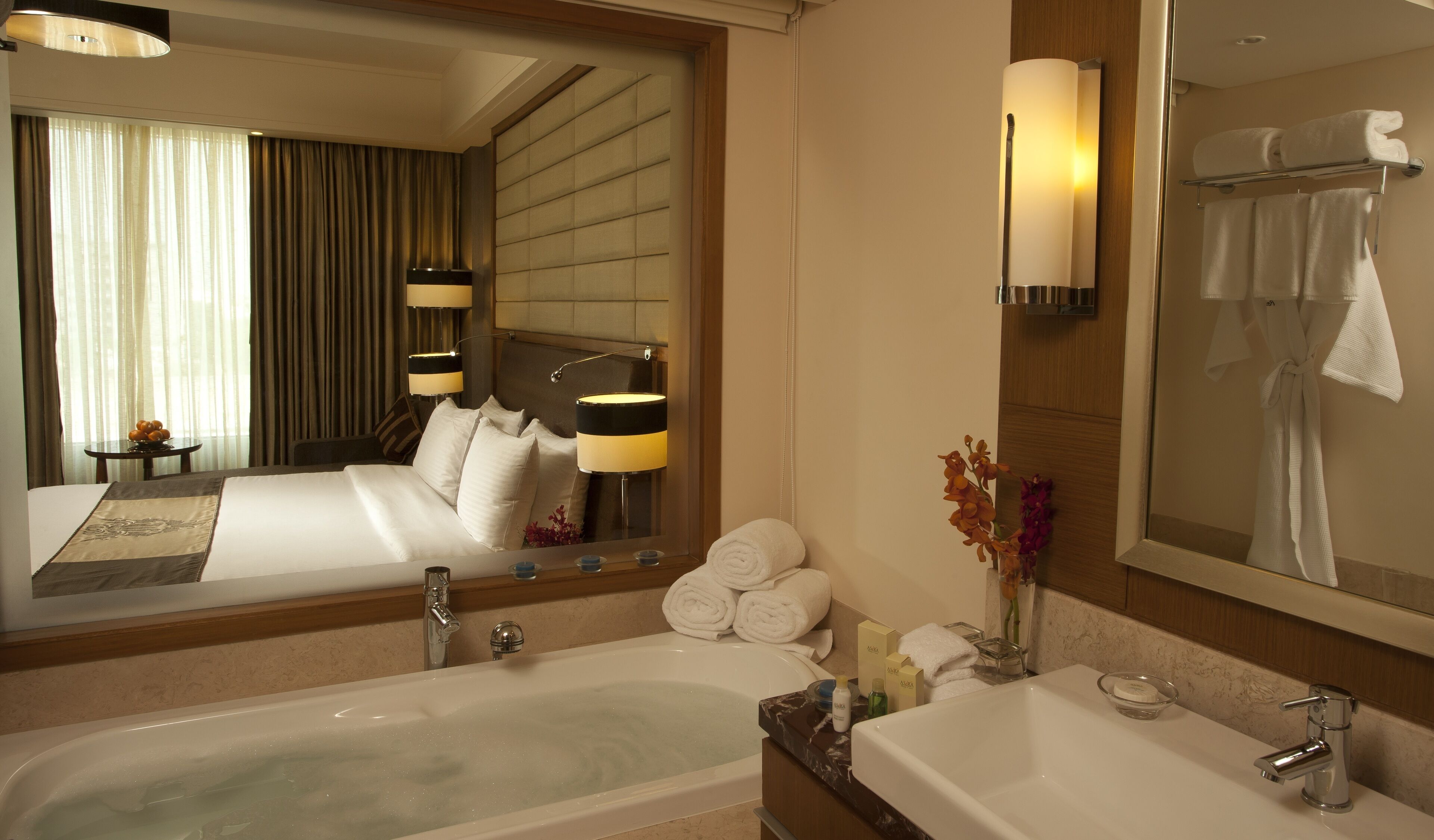 Une salle de bain d’hôtel avec une baignoire, un lavabo et un grand miroir. On y trouve des serviettes et des articles de toilette sur le comptoir.