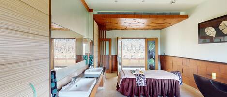 A hotel room with a large bed, two sinks, a bathtub, and a large mirror.