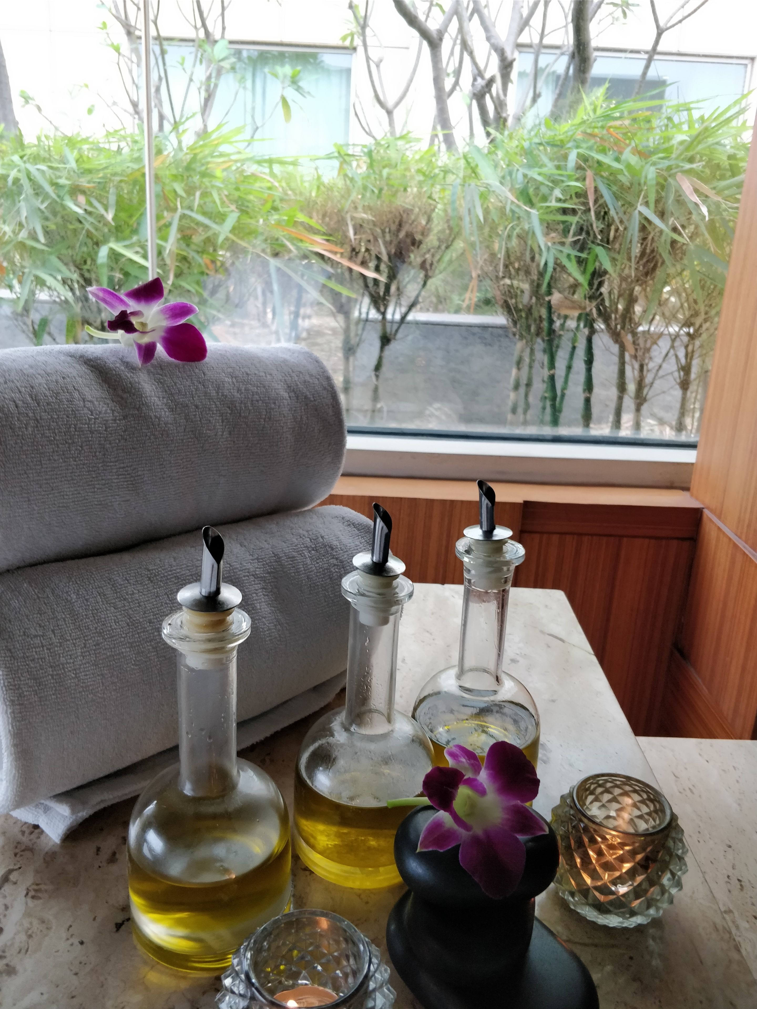 Una habitación con vistas a la vegetación, un sofá y varias botellas y una vela sobre una mesa.