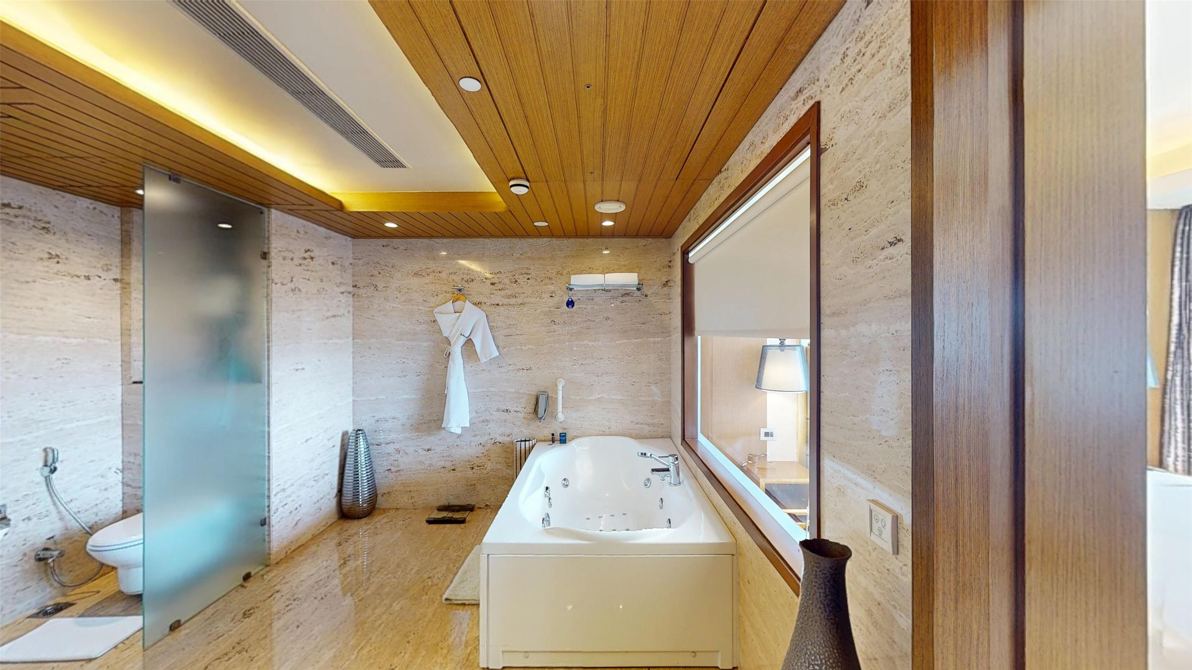 Ein modernes Badezimmer mit Holzboden, einem großen Spiegel, einer Badewanne und einer Toilette.