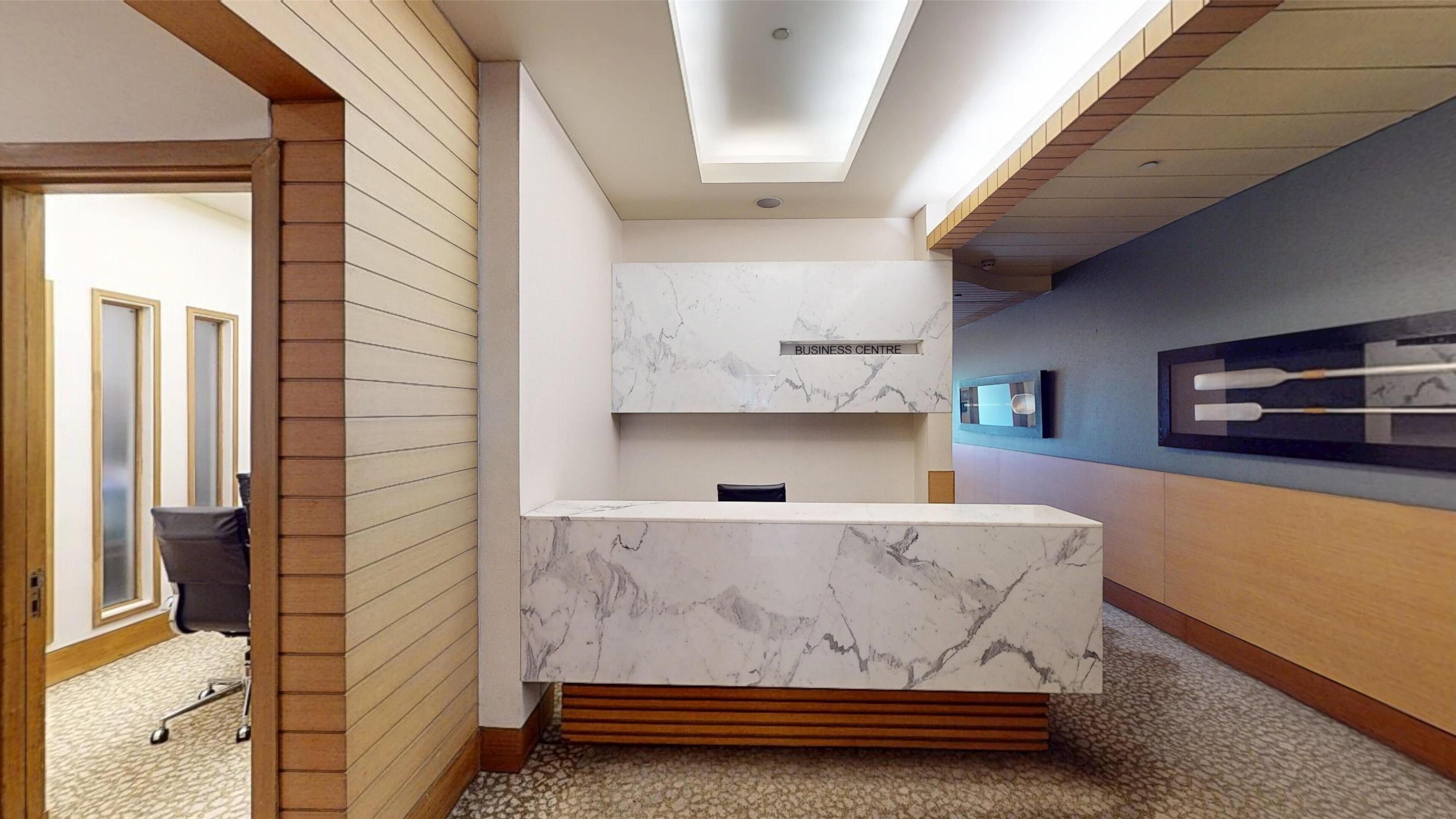 A modern reception area with a marble counter, wooden accents, and a ceiling with recessed lighting.