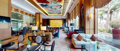 A hotel lobby with a bar area, seating arrangements, and a large mural on the ceiling.