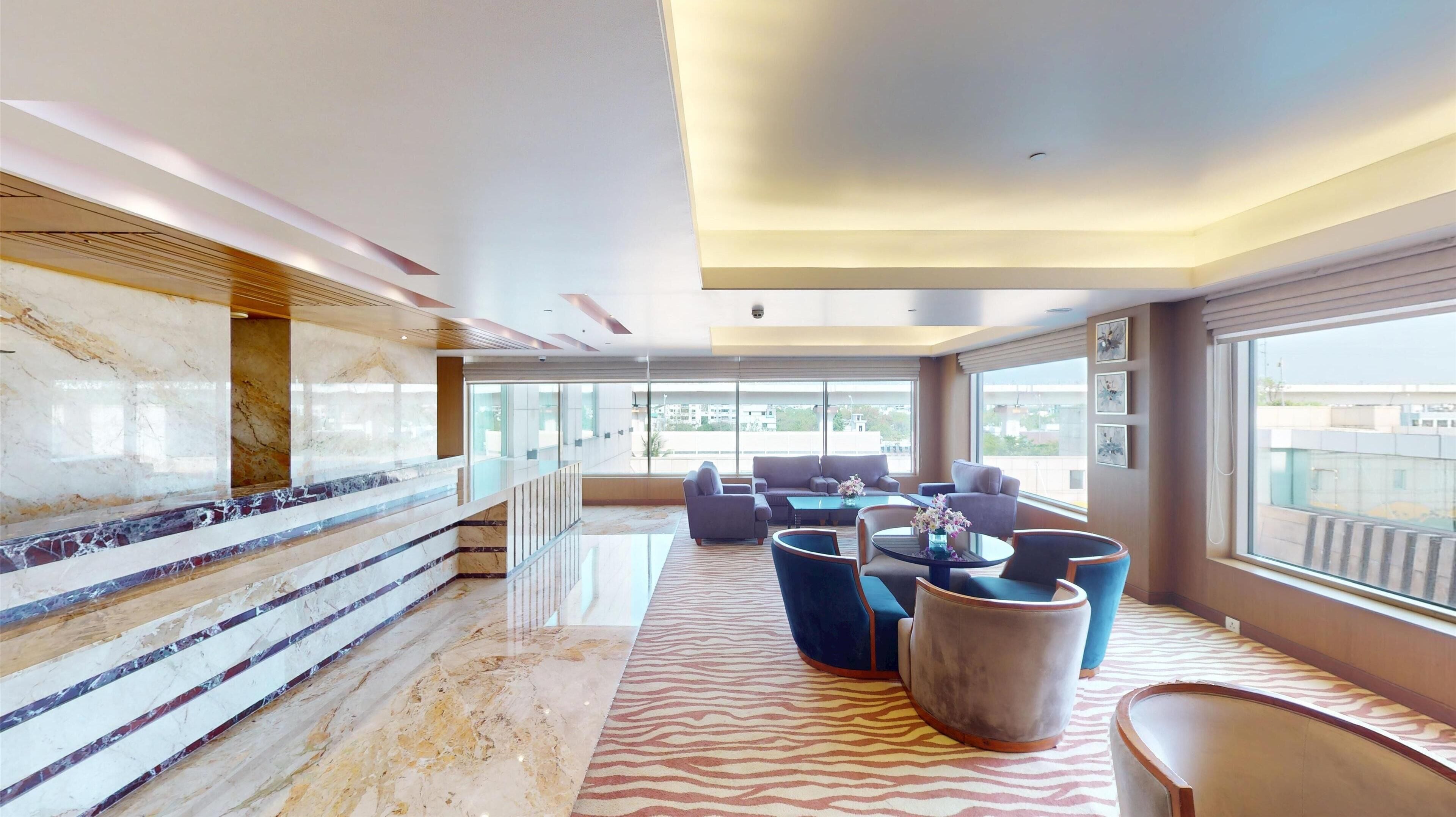 A spacious lobby with a marble staircase, comfortable seating, and large windows offering a view of the city.