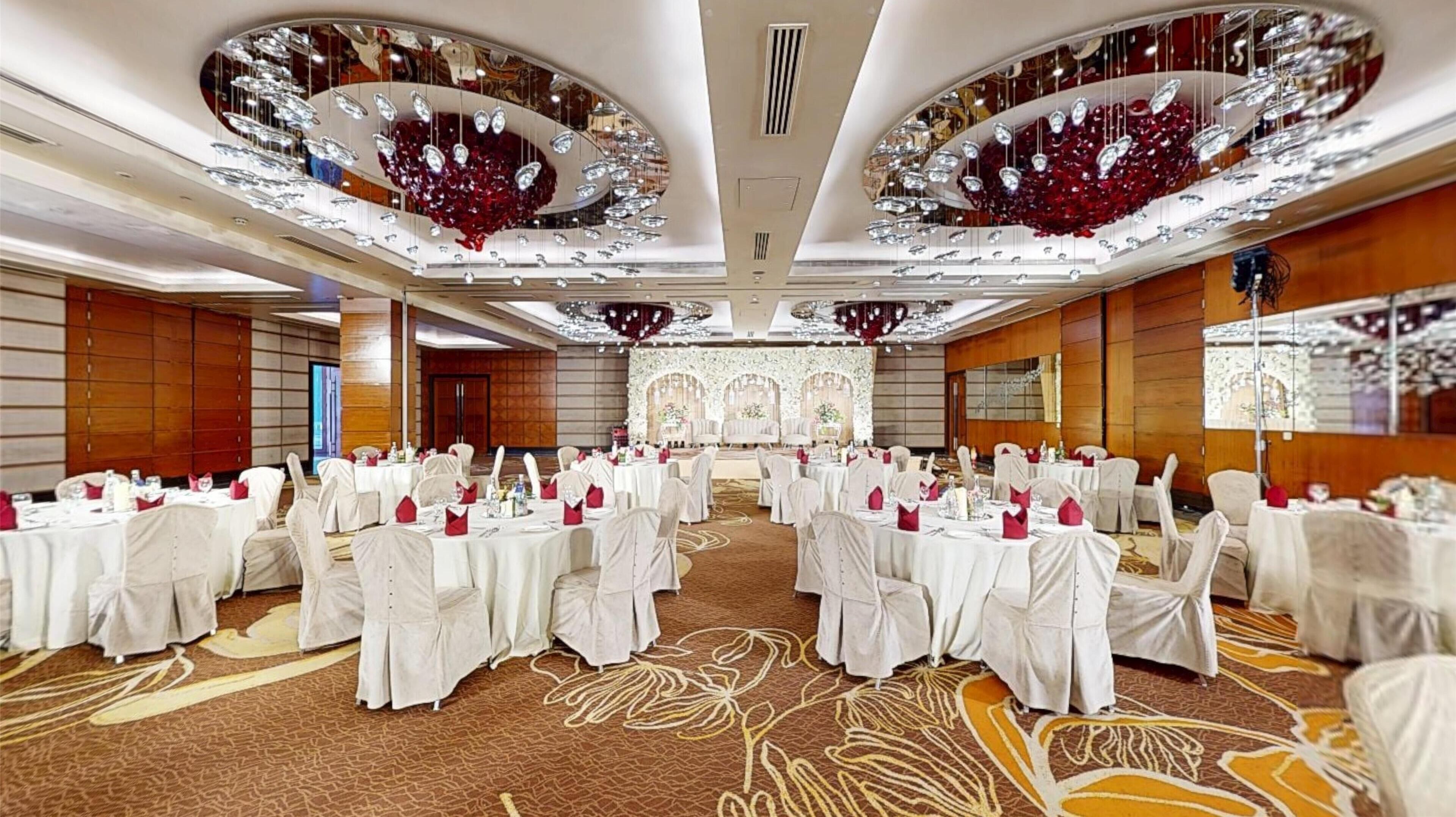 A banquet hall with round tables, white tablecloths, and red napkins.