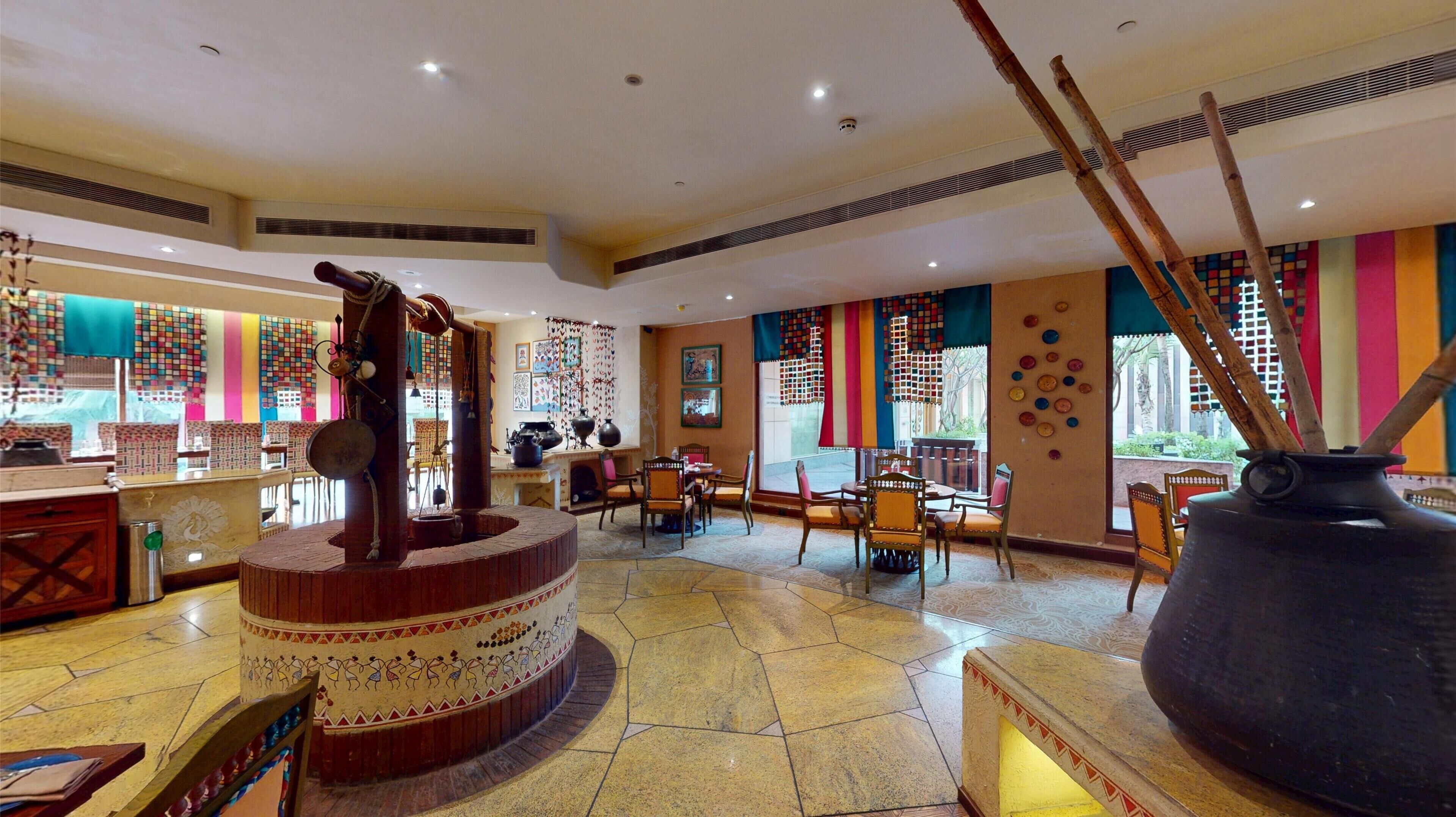 A traditional restaurant interior with a central fire feature, wooden furniture, and colorful wall decorations.