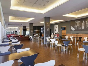 Un restaurante moderno con diversas opciones de asientos, como mesas y cabinas, y una zona de bar.