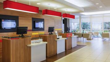Una moderna zona de recepción con varios mostradores de entrada, pantallas digitales y vistas al exterior.