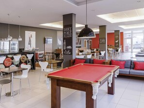 Tavolo da biliardo, area salotto e bancone della cucina in un caffè.