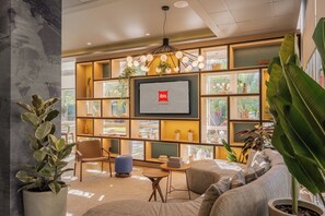A modern living room with a large TV screen, comfortable seating, and a variety of decorative items. - Ibis Canoas Shopping (Canoas)