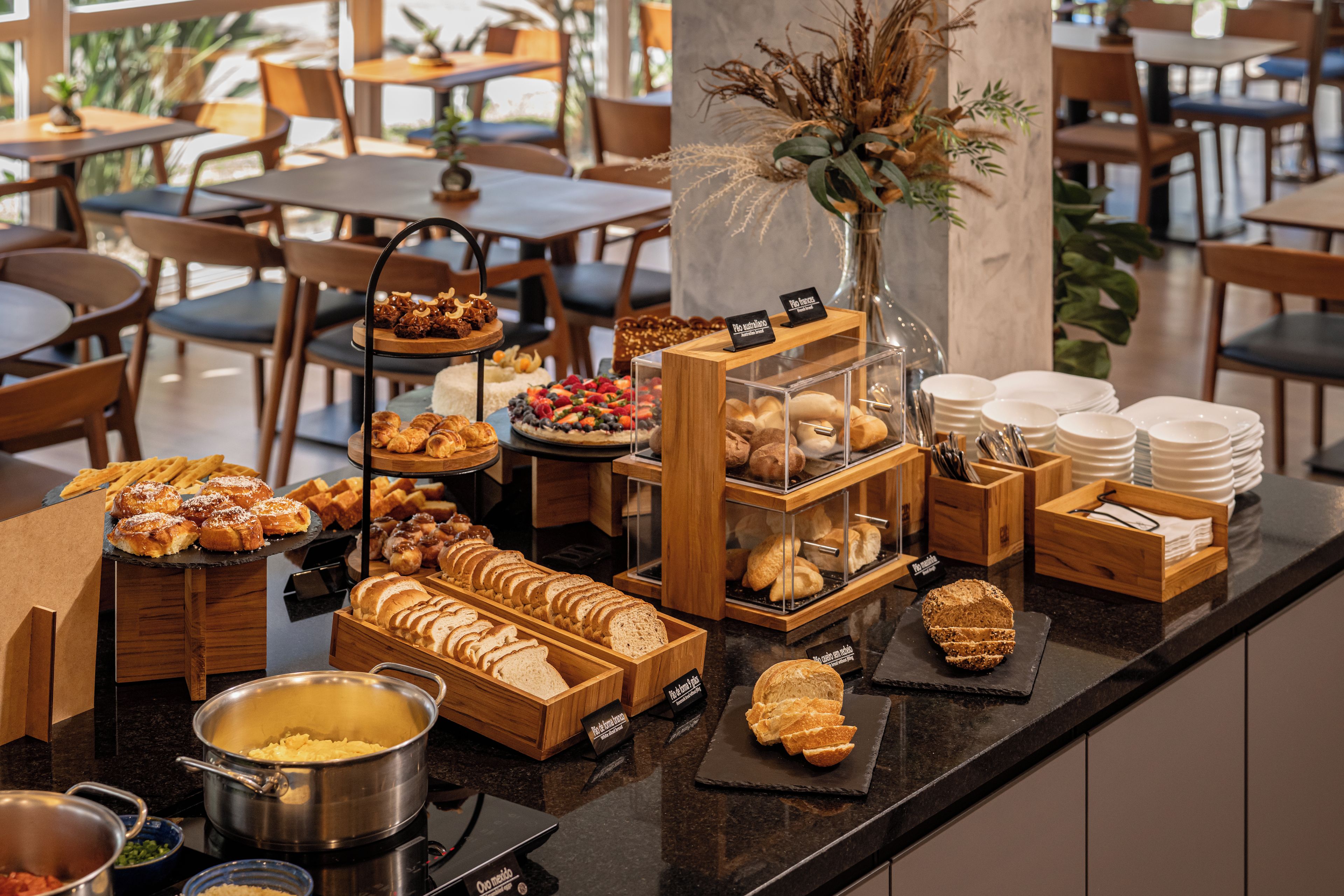 A buffet counter with various food items, including pastries, bread, and a selection of fruits.