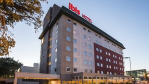 Un hotel de varios pisos con un letrero grande que dice "ibis Hotel" en el techo.