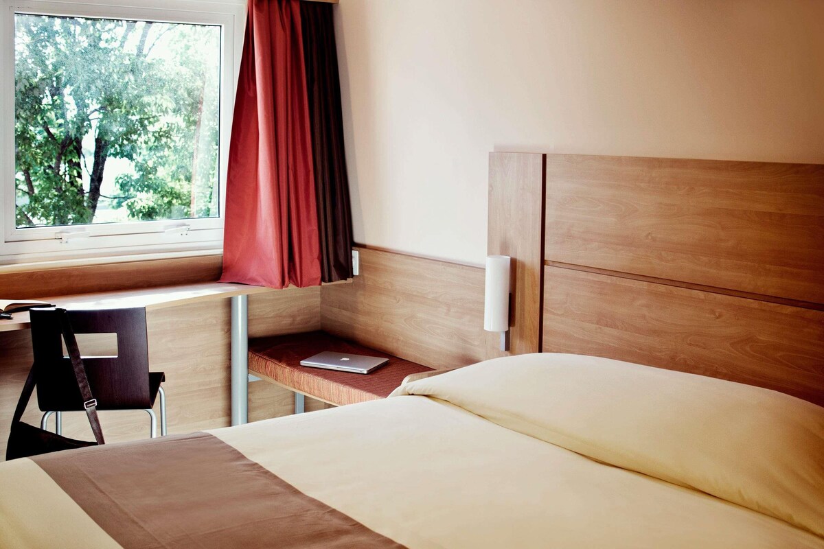 Een hotelkamer met een bed, een bureau en een stoel.