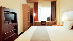 A hotel room with a bed, TV, closet, desk, and window with curtains. - Ibis Canoas Shopping (Canoas)