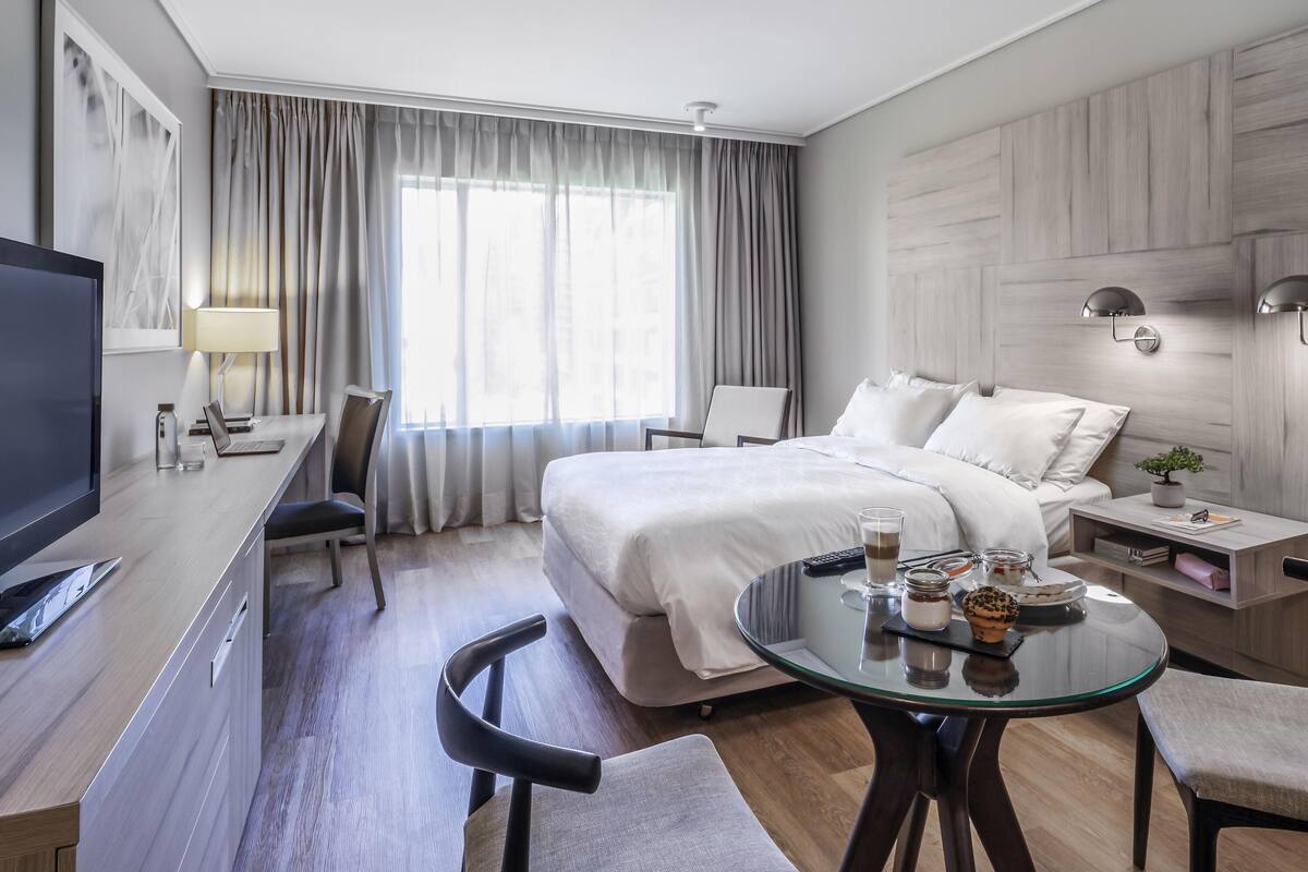 Une chambre d’hôtel moderne équipée d’un lit, d’un bureau et d’un coin salon.