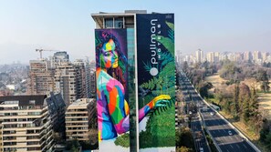 A tall building with a large mural featuring a colorful abstract figure and a green leafy design. - Pullman Santiago Vitacura (Santiago)