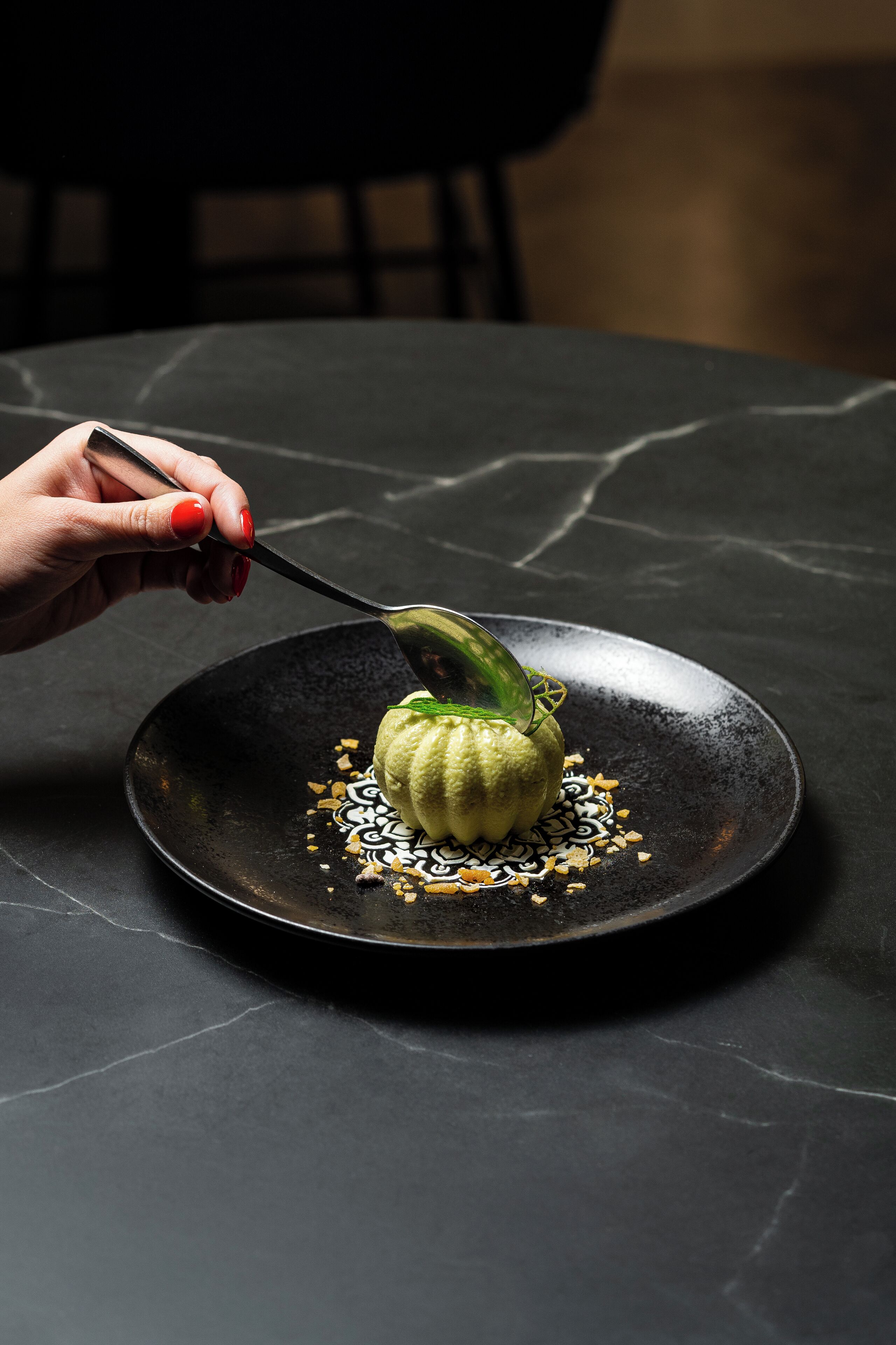 Una mano sirve un plato sobre un plato negro con una cuchara.