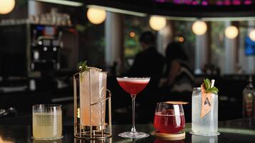 A bar with various drinks, including a martini, a cocktail with a red drink, and a clear drink with a mint garnish.