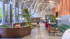 Een moderne lobby met een gebogen zitgedeelte, een receptiebalie en een groot raam met uitzicht op de omgeving.