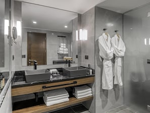 A modern bathroom with a large mirror, two sinks, a wooden vanity, and a glass shower enclosure.