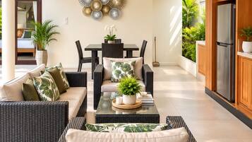 A modern living area with wicker furniture, a ceiling fan, and a dining table with chairs.