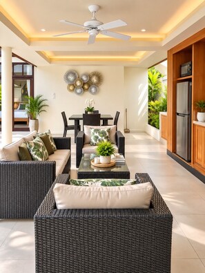 A modern living area with wicker furniture, a ceiling fan, and a dining table with chairs.